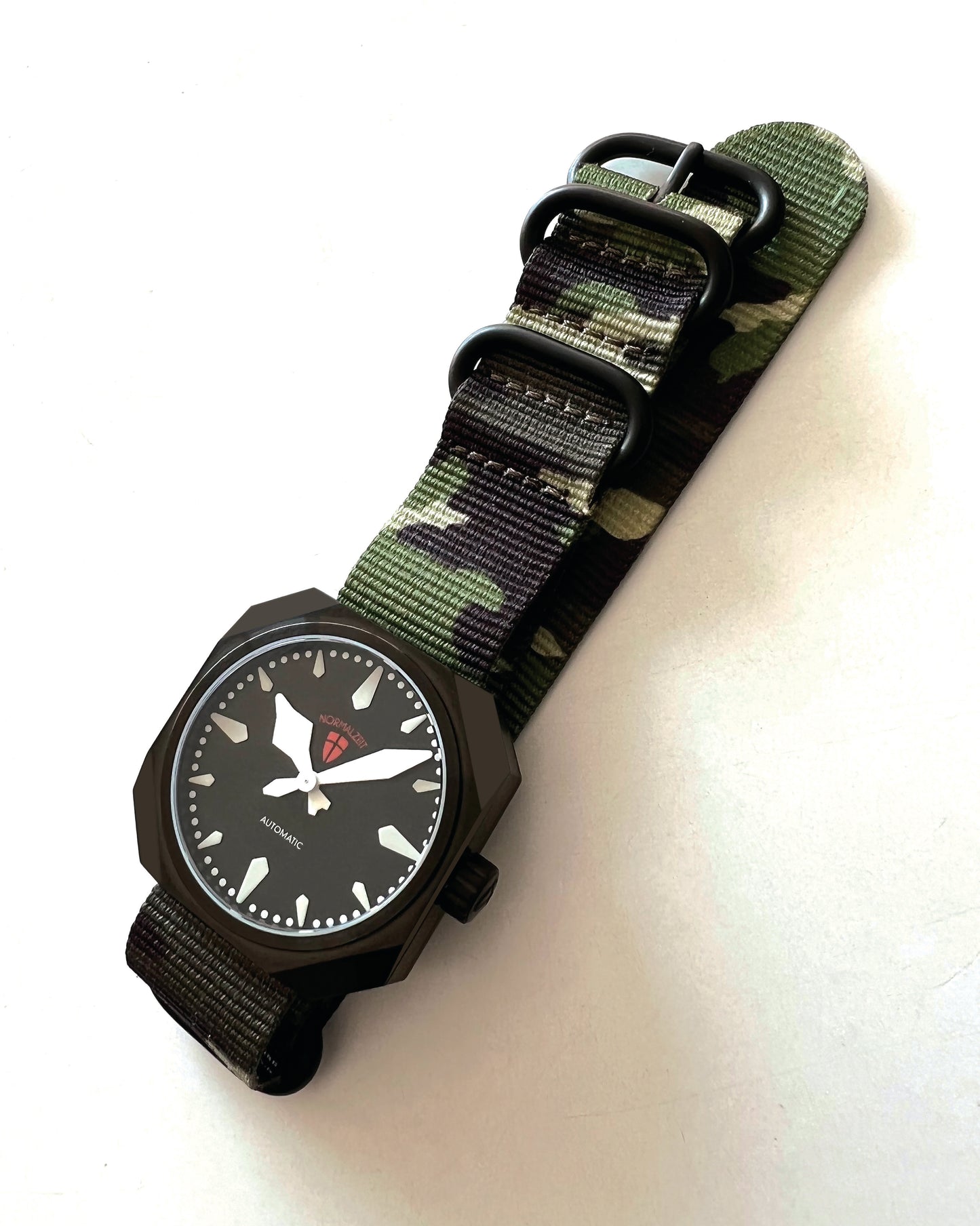 Normalzeit Der Kapitän DLC black automatic watch laid flat with camouflage nylon strap fully extended